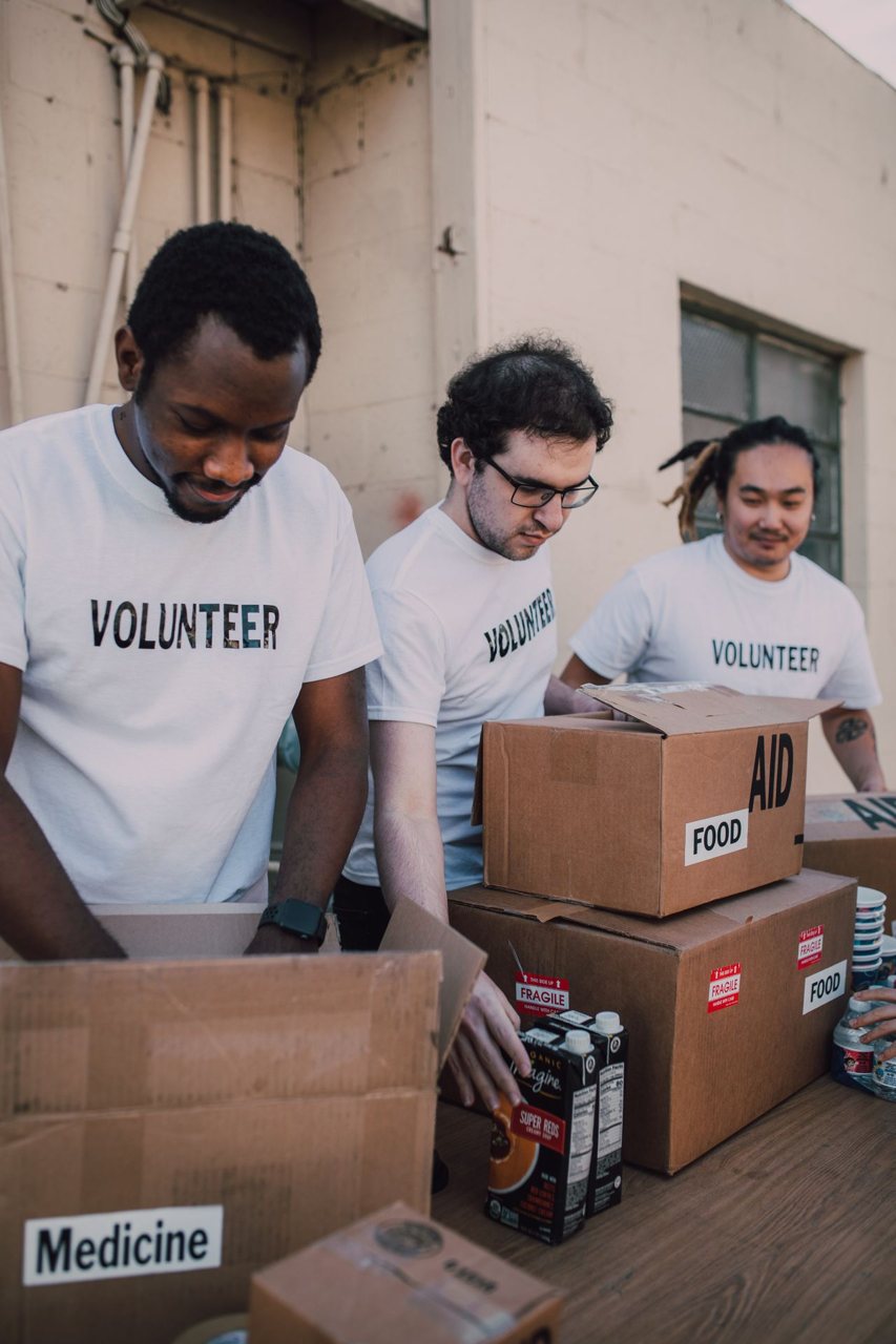 Free Group of volunteers preparing food and medicine boxes for charity distribution. Stock Photo