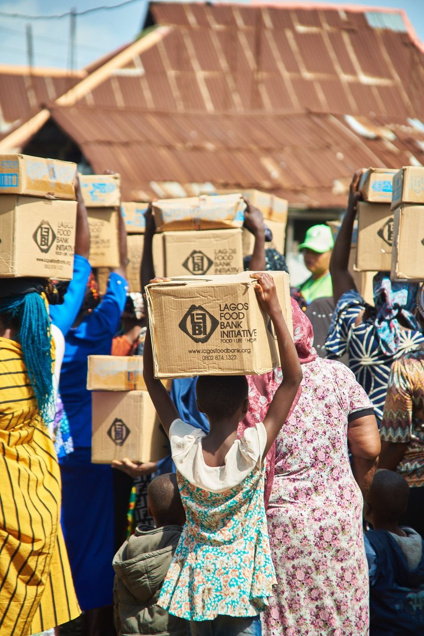 Free A group of people carrying boxes from Lagos Food Bank Initiative during a community support event. Stock Photo